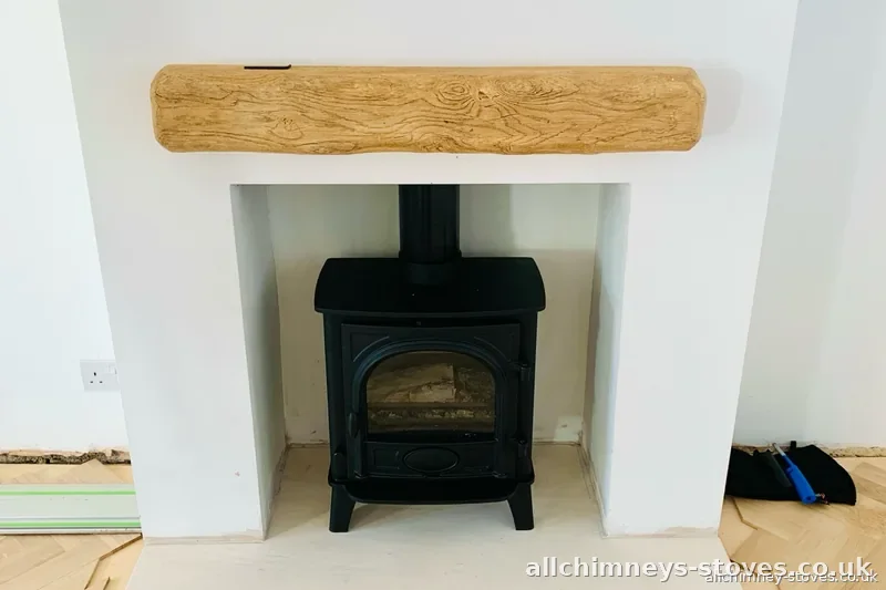 HETAS certified wood burner installation — cast iron stove, oak beam mantel, plastered opening, Allchimney Stoves, Upminster